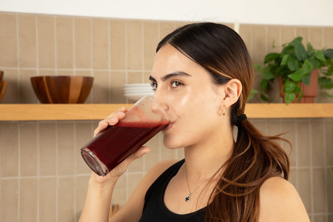 A woman drinking a glass of Liv120 in her kitchen